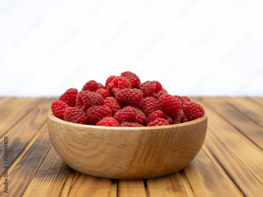 Fresh raspberries in wooden bowl on wooden background. With copy space for text Fresh raspberries in wooden bowl on wooden background. With copy space for text
