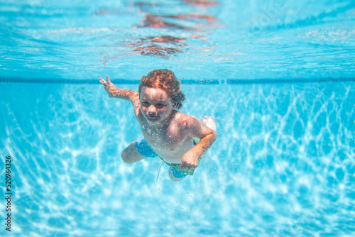 Underwater kids swims in pool, healthy child swimming and having fun under water.