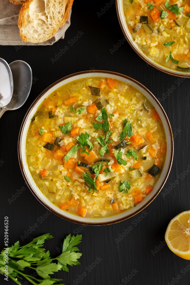 Homemade fresh lemon rice soup in a bowl on a black surface, top view. Flat lay, overhead, from above. Homemade fresh lemon rice soup in a bowl on a black surface, top view. Flat lay, overhead, from above.