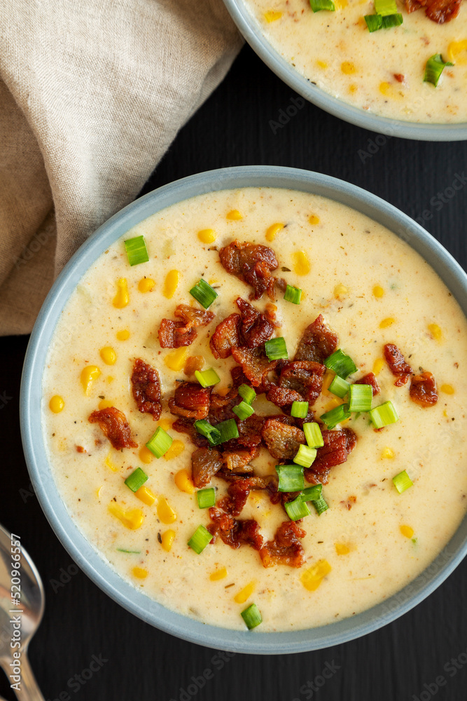 Homemade Corn Chowder with Bacon in a Bowl on a black surface, top view. Flat lay, overhead, from above. Homemade Corn Chowder with Bacon in a Bowl on a black surface, top view. Flat lay, overhead, from above.