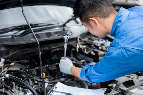 Service outdoor. Asian auto mechanic man working on car engine using wrench to repair and maintenance, broken car care check and fixed the problem and services insurance