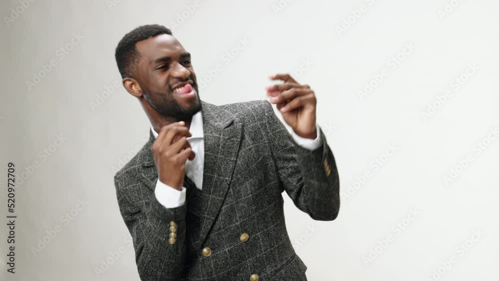 An African-American businessman dances in the studio in a business suit and enjoys Friday, weekends and time off from work An African-American businessman dances in the studio in a business suit and enjoys Friday, weekends and time off from work