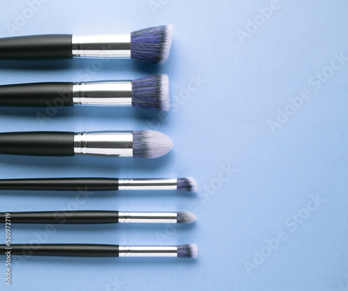 Creative concept beauty fashion photo of cosmetic product make up brushes kit on blue background.