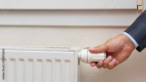 Man's hand adjusting the temperature of a radiator. front view