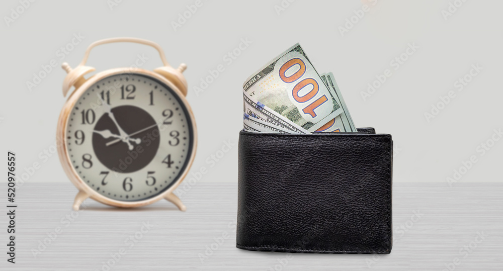 time and money concept. Clock and 100 dollars on the table. Front view time and money concept. Clock and 100 dollars on the table. Front view