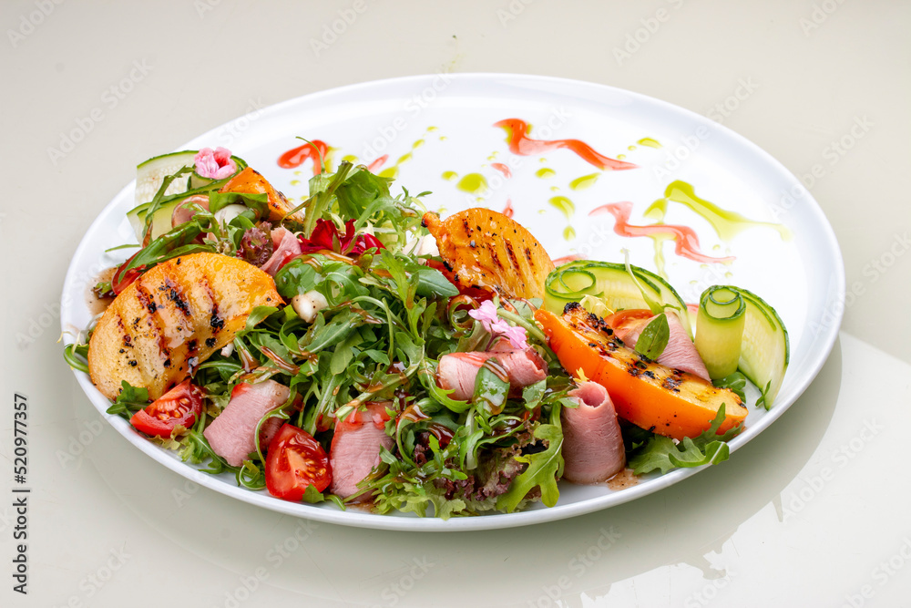 Fresh salad with ham and arugula, with grilled persimmon.