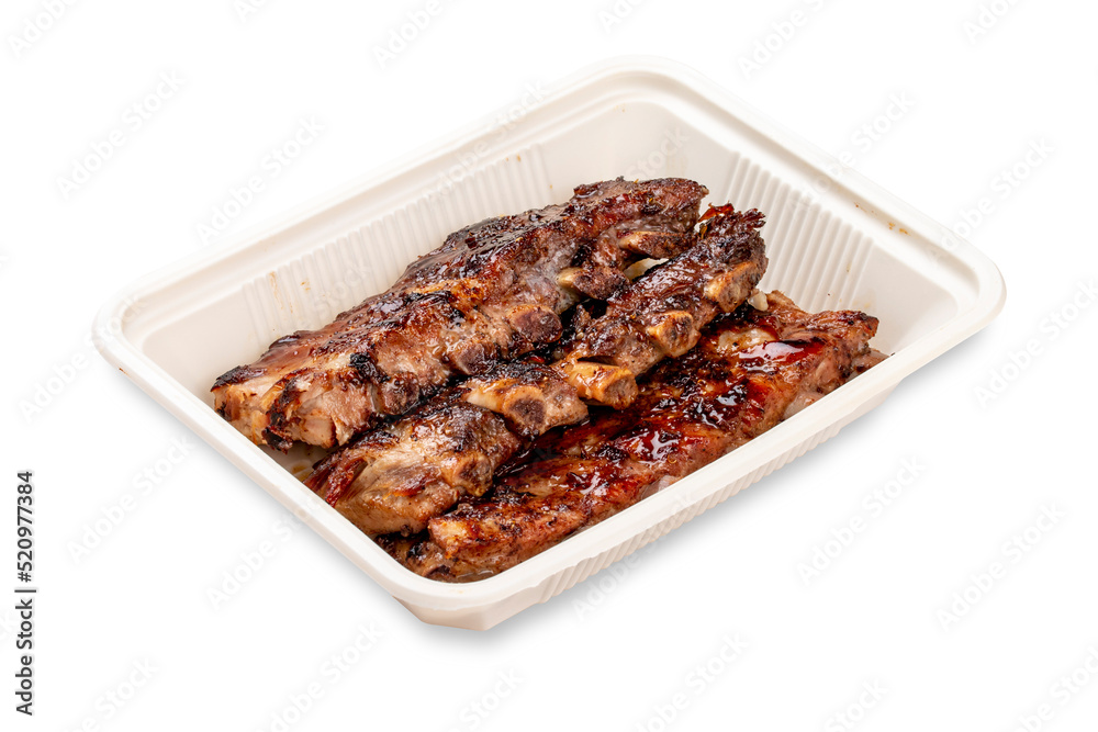 Grilled pork ribs. In a plastic container. Food to go. On a light background. Grilled pork ribs. In a plastic container. Food to go. On a light background.