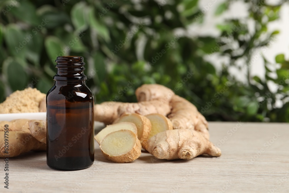 Naklejka premium Ginger essential oil in bottle on wooden table. Space for text