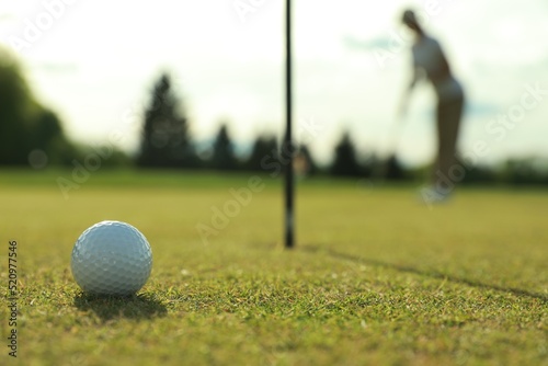 Woman playing golf at green course, focus on ball. Space for text