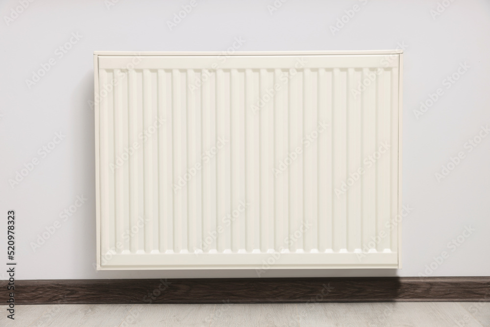 Modern radiator on white wall in room. Central heating system Modern radiator on white wall in room. Central heating system