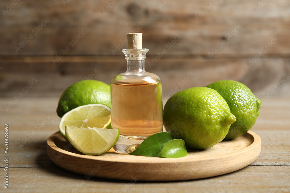 Lime essential oil and citrus fruits on wooden table Lime essential oil and citrus fruits on wooden table