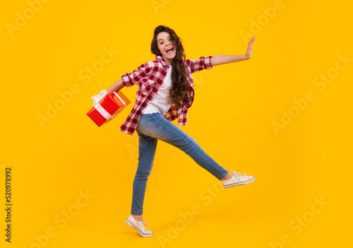 Amazed teenager. Child with gift present box on isolated studio background. Gifting for kids birthday. Excited teen girl.