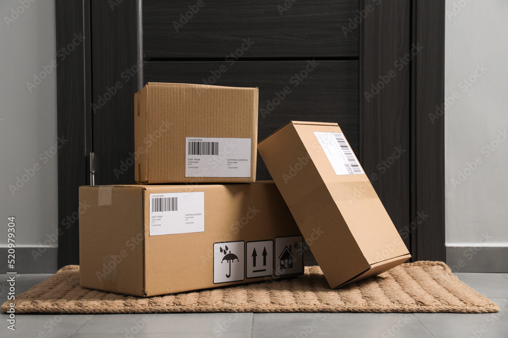 Cardboard boxes on floor mat near entrance. Parcel delivery service - obrazy, fototapety, plakaty 