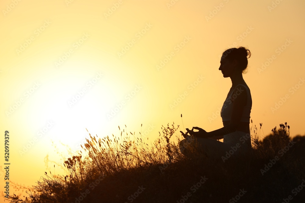 Silhouette of woman meditating outdoors at sunset. Space for text