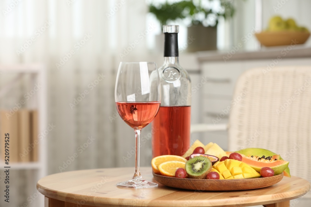 Delicious exotic fruits and wine on wooden table indoors