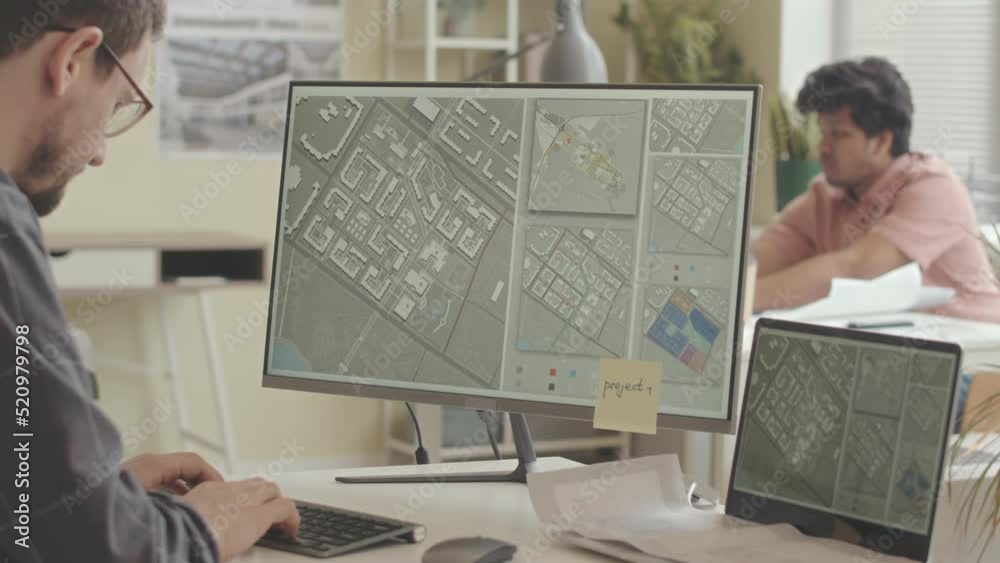 Waist up slowmo of professional city planner typing on computer while developing city urbanization project in office