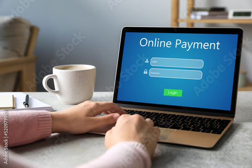 Woman using laptop for online payment at table, closeup