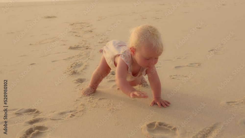Cute funny small baby Caucasian baby little daughter newborn toddler infant crawling on all fours steps walking on sandy shore near ocean sea have fun playing outdoors in summer day child development Cute funny small baby Caucasian baby little daughter newborn toddler infant crawling on all fours steps walking on sandy shore near ocean sea have fun playing outdoors in summer day child development