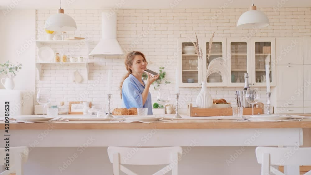 red headed woman holding mobile phone talking on speakerphone or voice messaging female dressed casual at home red headed woman holding mobile phone talking on speakerphone or voice messaging female dressed casual at home