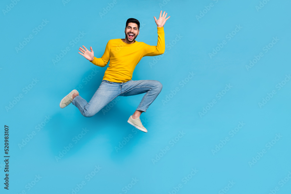 Full length photo of sportive energetic person jumping raise hands empty space isolated on blue color background