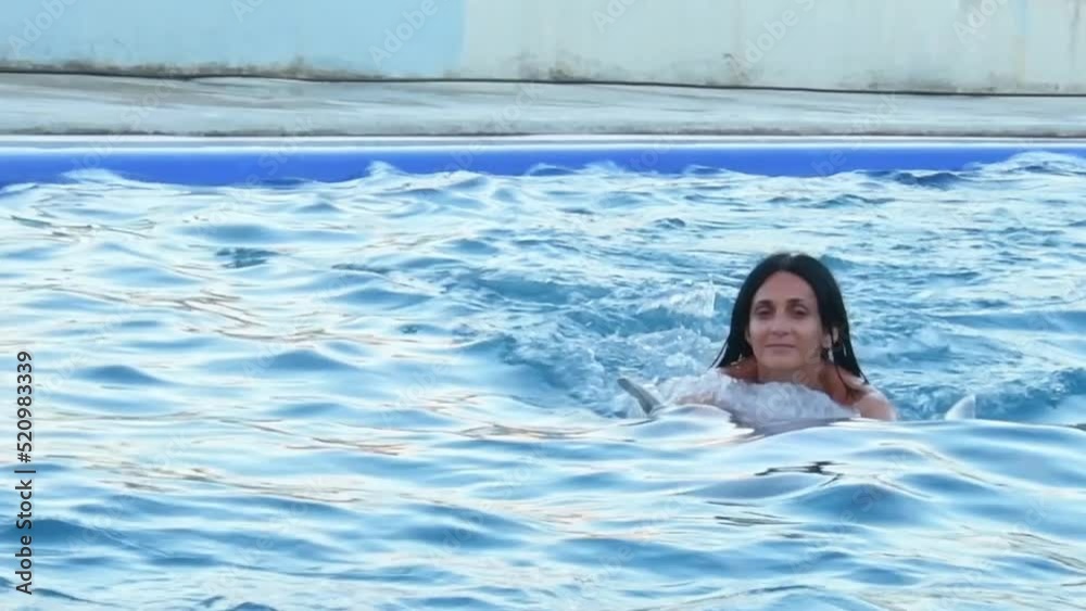 Caucasian woman swim with dolphin in pool. Batumi swim with dolphin experience concept Caucasian woman swim with dolphin in pool. Batumi swim with dolphin experience concept