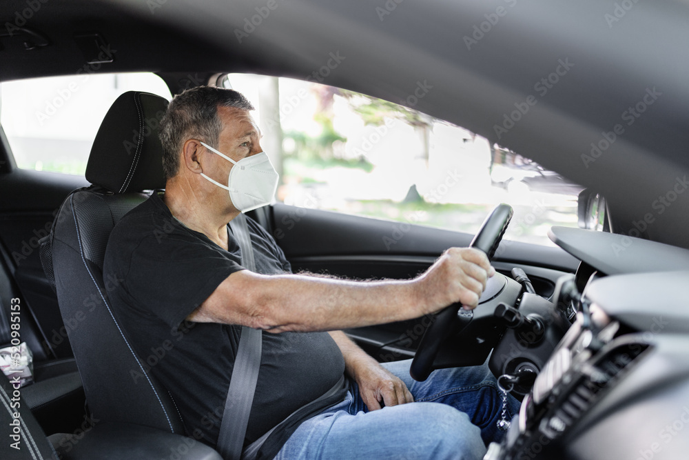 Senior in his 70s driving car wearing a face mask Senior in his 70s driving car wearing a face mask