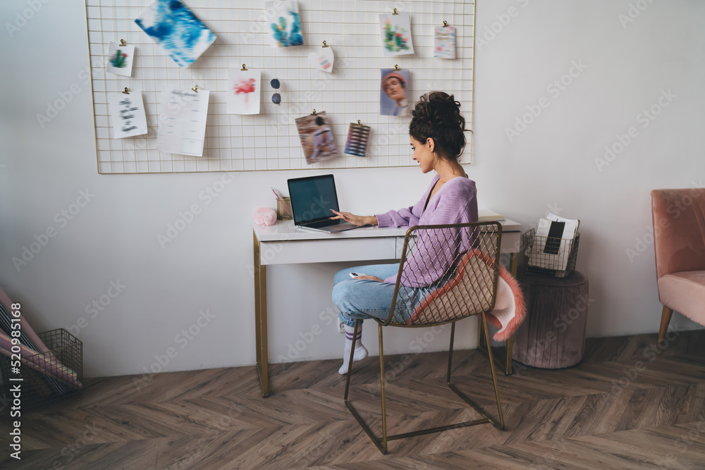 Young millennial woman freelancer work remote at home sitting at table with laptop computer device. Female student learning online with webinar course while using portable netbook for distantly study Young millennial woman freelancer work remote at home sitting at table with laptop computer device. Female student learning online with webinar course while using portable netbook for distantly study