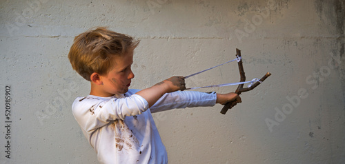 Valokuvatapetti Dirty boy aiming with a slingshot