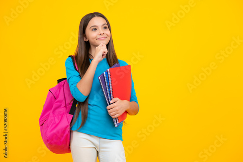Schoolchild, teenage student girl hold book on yellow isolated studio background. School and education concept. Back to school. Thinking face, thoughtful emotions of teenager girl.