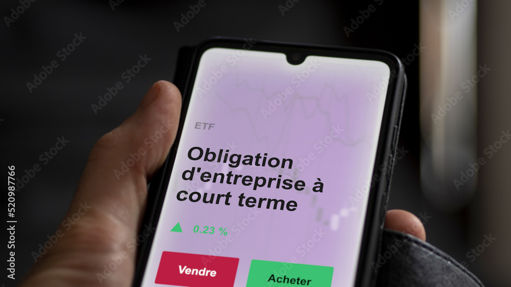 Un investisseur analyse un fonds etf obligation d'entreprise à court terme sur un graphique. Un téléphone affiche le cours de l'ETF. Texte en français francais Obligation d'entreprise à court terme