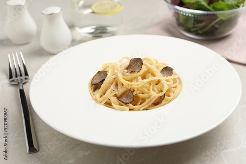 Delicious pasta with truffle slices and cheese served on light grey table