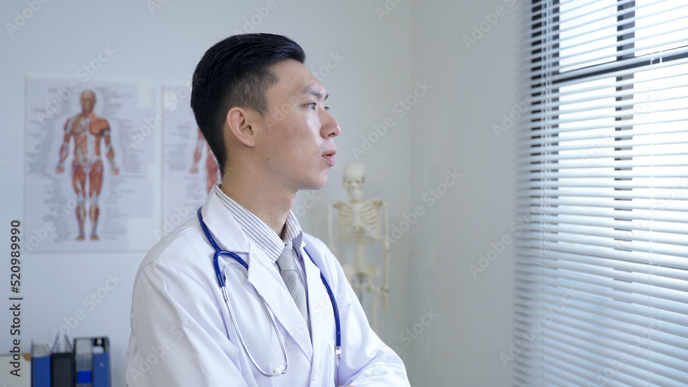 portrait handsome doctor is gazing outside by the window in contemplation at a bright clinic. portrait handsome doctor is gazing outside by the window in contemplation at a bright clinic.