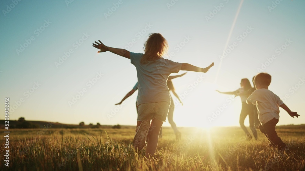 © maxximmm - kids run in the park at sunset. friendly family children camp kid dream concept. a group of children run on the grass at fun the rays of the sun silhouette. childhood sunset dream teamwork concept