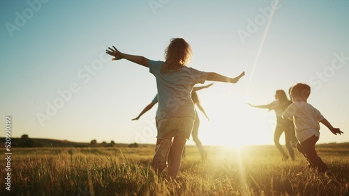 kids run in the park at sunset. friendly family children camp kid dream concept. a group of children run on the grass at fun the rays of the sun silhouette. childhood sunset dream teamwork concept