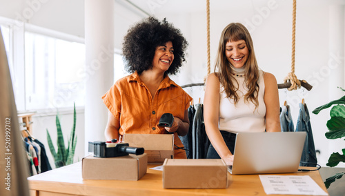 Cheerful clothing store owners preparing online orders for shipping photo