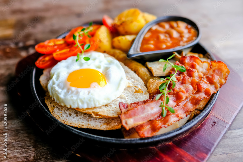 Delicious English breakfast with a fries egg, beans, bacon, and roasted potatoes. Delicious English breakfast with a fries egg, beans, bacon, and roasted potatoes.