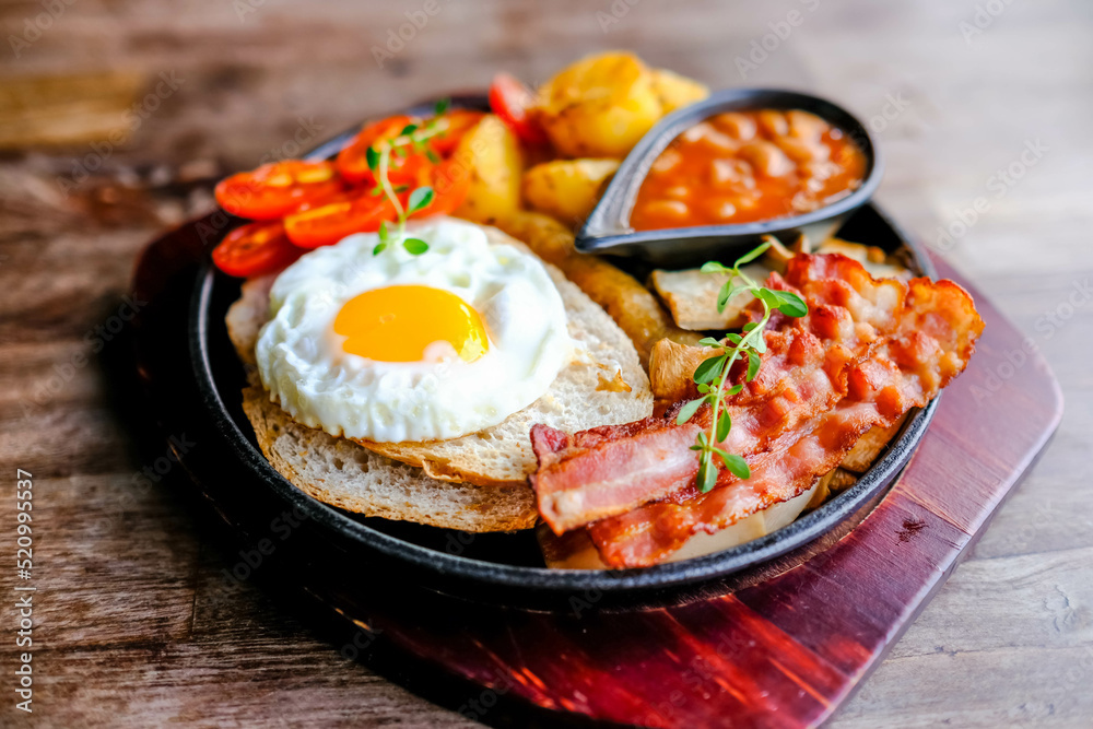 Delicious English breakfast with a fries egg, beans, bacon, and roasted potatoes. Delicious English breakfast with a fries egg, beans, bacon, and roasted potatoes.