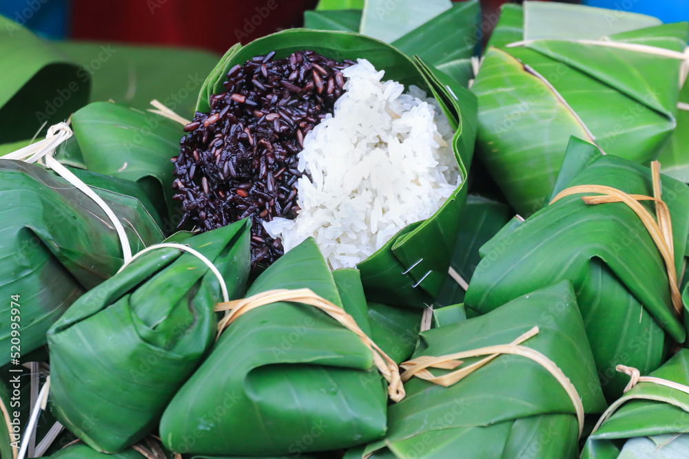 Thai steamed black and white sticky rice wrapped in banana leaf package ...