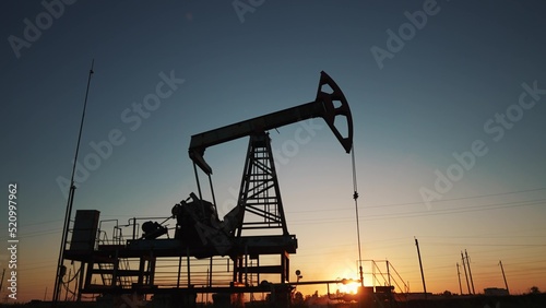 oil production. silhouette oil and gas production rig at sunset glare. oilfield business a extraction concept. oil extraction pump. lifestyle Oil pump rig photo