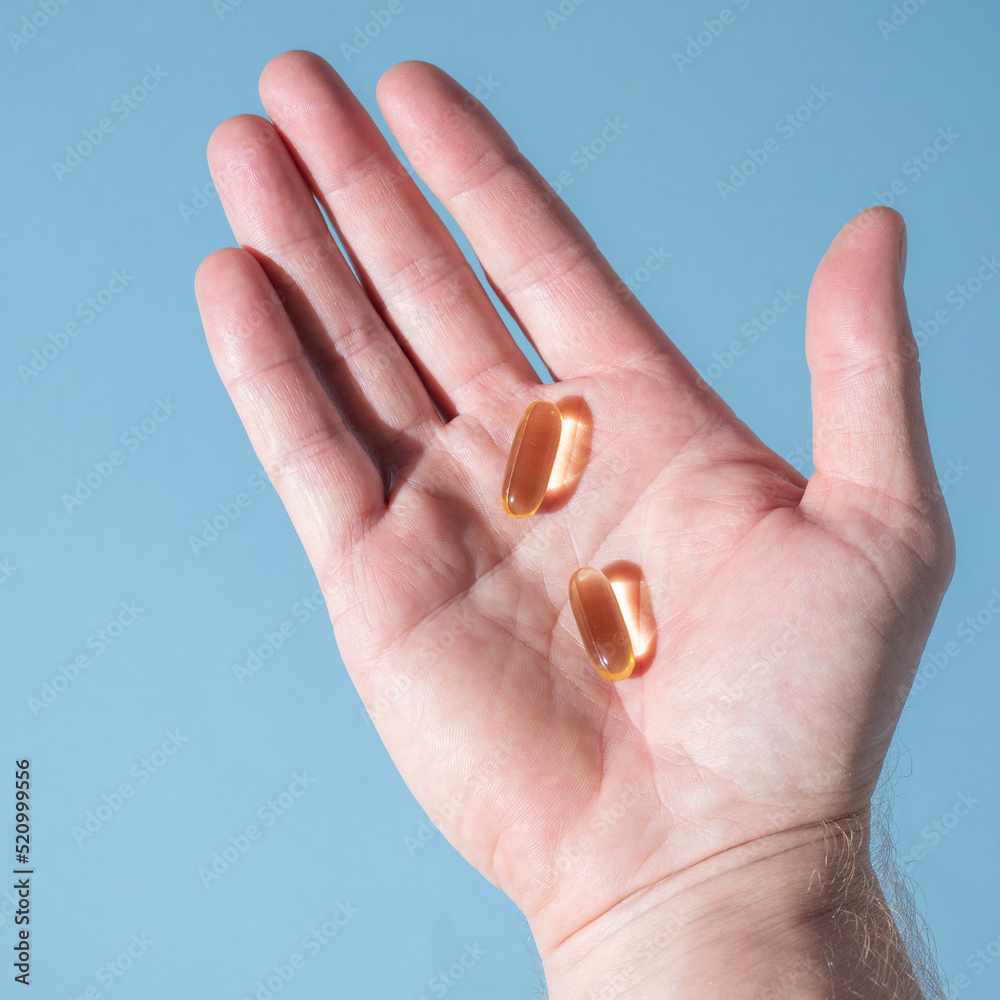 Foto de Two fish oil pills on the palm of the right hand with pastel