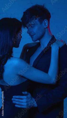 vertical video of attractive woman seducing man in blazer on blue