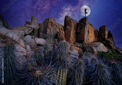 silhouette of a womn on a rock in a yoga position at night connecting with the stars photo