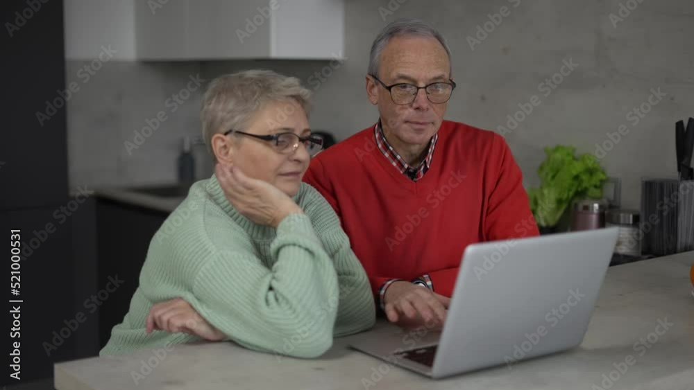 Sad pensioners looking at laptop, discussing utility bills, financial problem or confusing news Sad pensioners looking at laptop, discussing utility bills, financial problem or confusing news