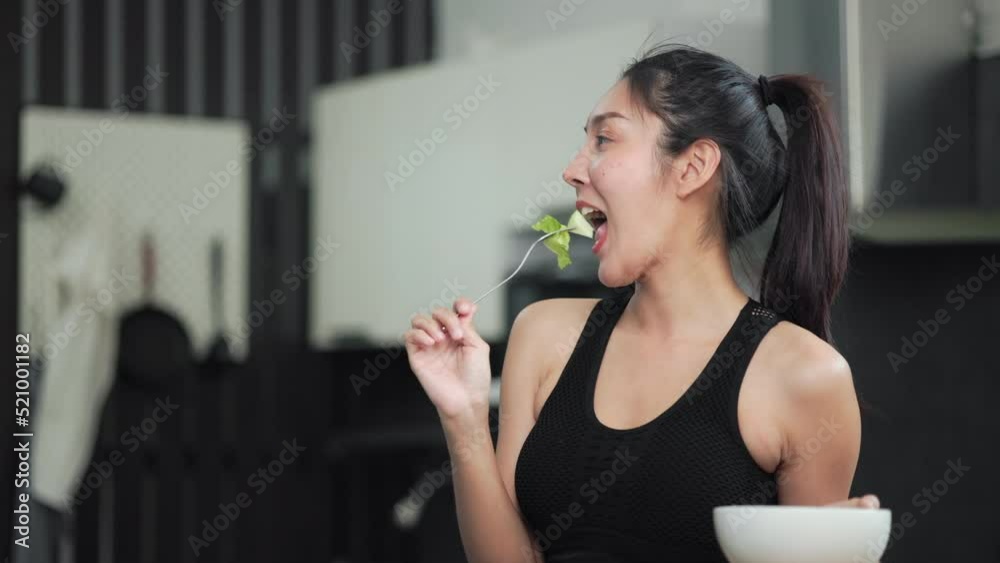 Young female eating organic greens vegetable salad in weight loss diet and wellness on table. Beautiful woman happily eat a healthy salad breakfast in kitchen in the morning. Diet food concept. Young female eating organic greens vegetable salad in weight loss diet and wellness on table. Beautiful woman happily eat a healthy salad breakfast in kitchen in the morning. Diet food concept.