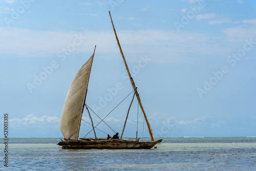 traditional african sailing outrigger canoes with sails against a blue sea and sky