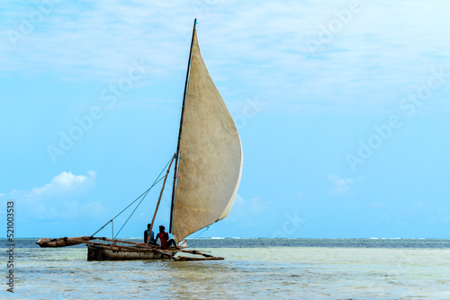 traditional african sailing outrigger canoes with sails against a blue sea and sky