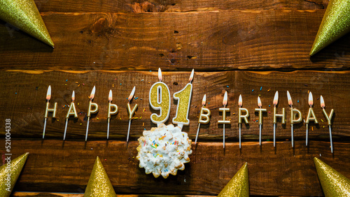 Photography golden letters of the candle with the number happy birthday, the background of the pie with candles happy birthday on the background of brown stranded boards
