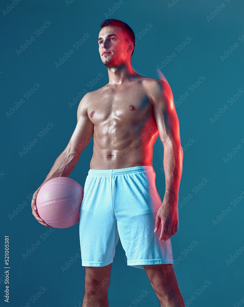 Male basketball player with naked muscular torso holding ball on blue  studio background. Long exposure. Sports workout Stock Photo | Adobe Stock