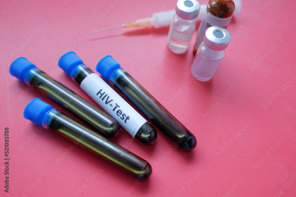 HIV blood test tubes and syringe on red background HIV blood test tubes and syringe on red background