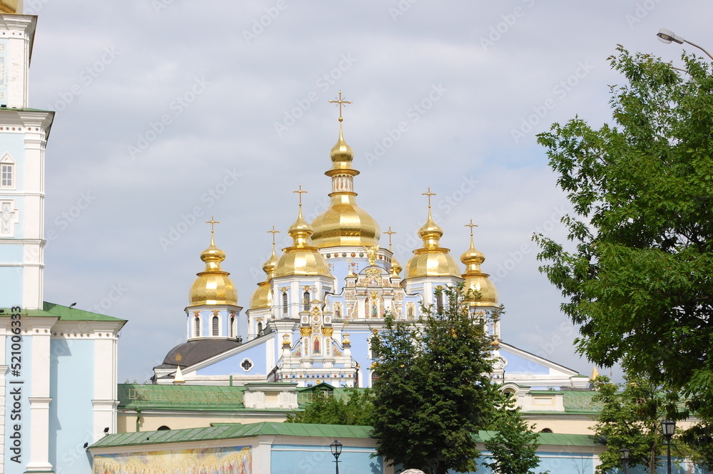 Cathedral of Kiev-Pechersk Lavryna . Golden domes of the Mikhailovsky Golden-Domed Cathedral against the background of a blue sky in Kiev, Ukraine. Orthodox temple of blue color, view from the outside